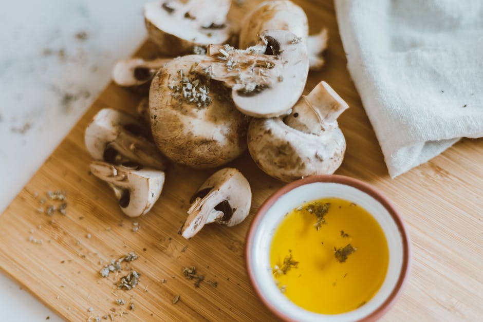 Close-up of sliced mushrooms and herb-infused oil on a wooden chopping board.