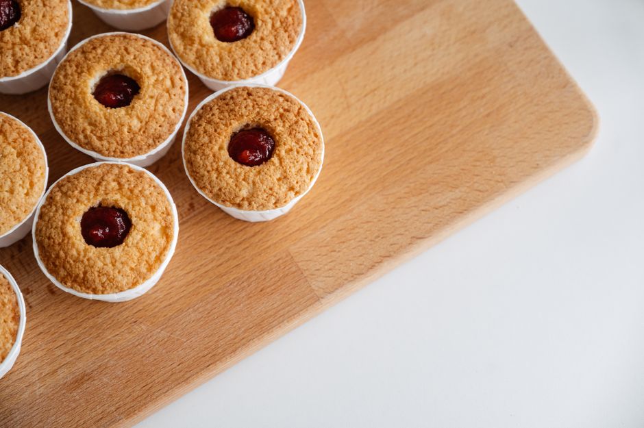 Delicious cherry topped cupcakes arranged on a wooden board, perfect for dessert lovers.