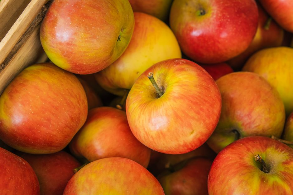 A vibrant close-up shot of ripe red and yellow apples in a wooden crate.