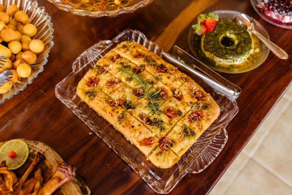 Delicious homemade tomato focaccia bread displayed with various appetizers on a rustic wooden table.