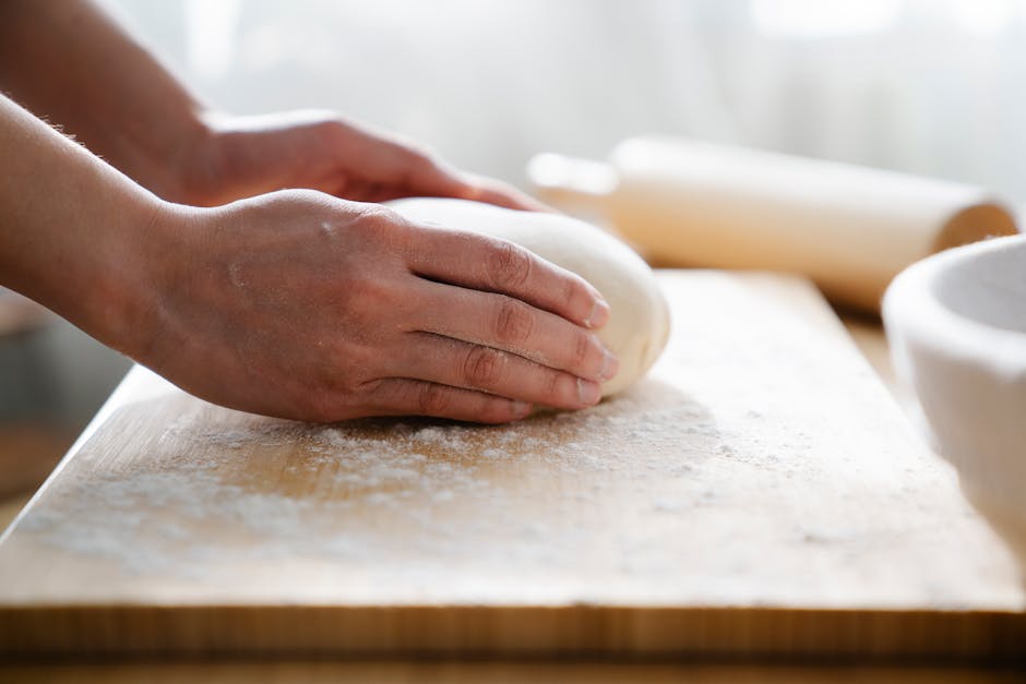 Close-up of hands kneading dough on a floured wooden board, perfect for baking themes.