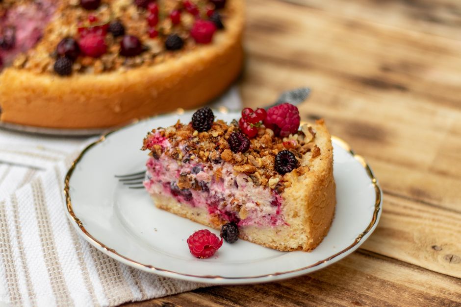 Close-up of a slice of berry tart on a white ceramic plate with a wooden background.