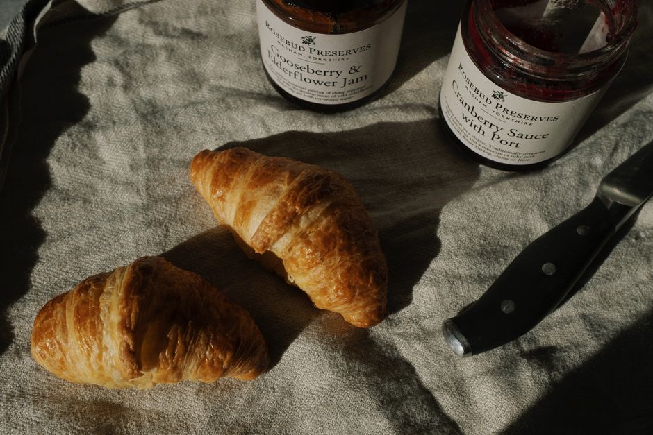 Delicious croissants ready to enjoy with gourmet jams. Perfect cosy breakfast setup.