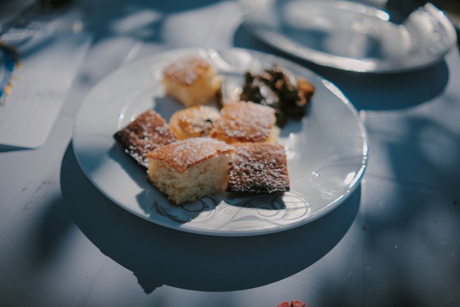 Close-up of cake pieces on a plate outdoors with summer sunlight.