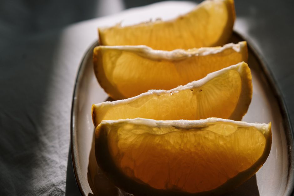 Close-up of juicy orange slices on a ceramic plate in natural light.