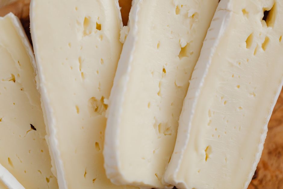 Close-up view of creamy cheese slices with a bloomy rind, perfect for culinary displays.