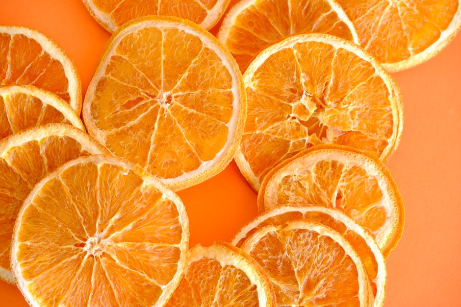 Close-up of juicy orange slices arranged on a bright orange background.