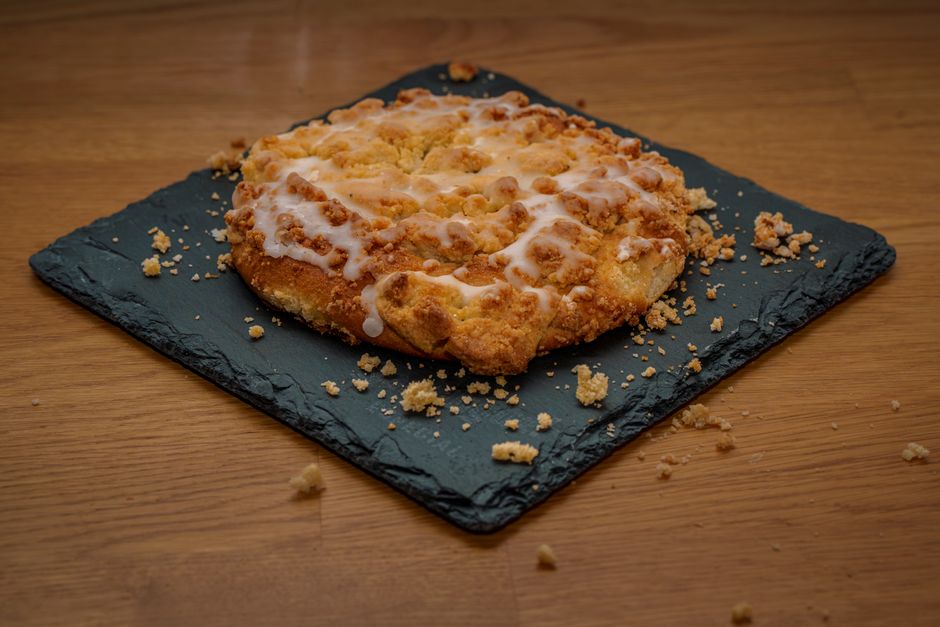 Delicious crumble dessert with icing on a black slate plate, on a wooden table.