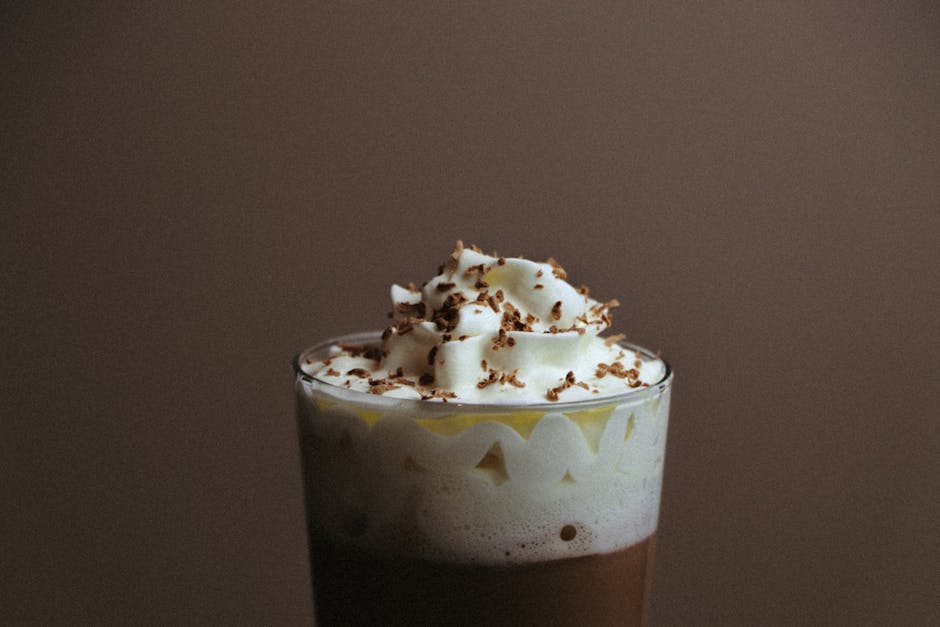 A close-up of a creamy cappuccino topped with whipped cream and chocolate shavings.