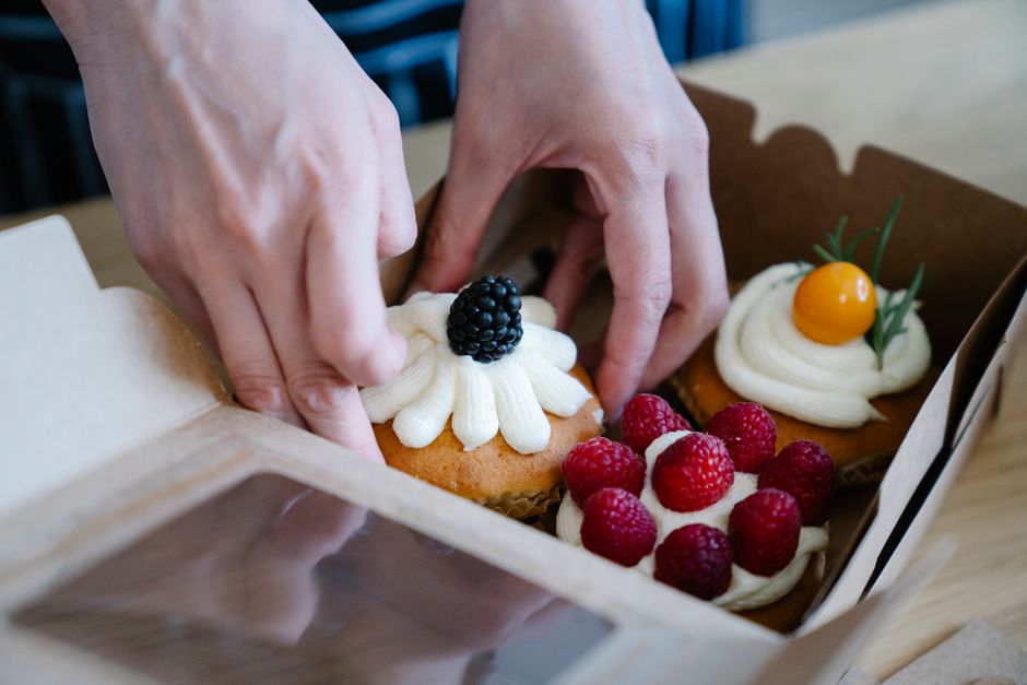 Freshly baked cupcakes with fruit toppings in a box
