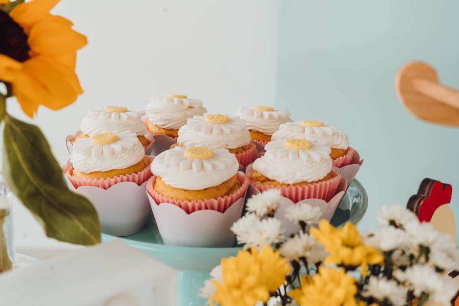Cupcakes with flower designs on a stand surrounded by spring flowers.