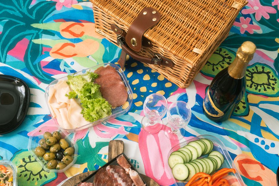 A vibrant picnic arrangement with food, wine, and a colorful blanket, perfect for summer outings.