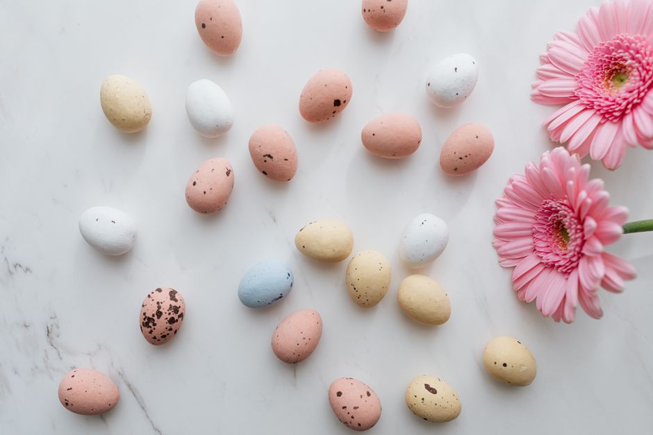 A beautiful arrangement of pastel Easter eggs and pink flowers on a marble surface, ideal for festive decor.