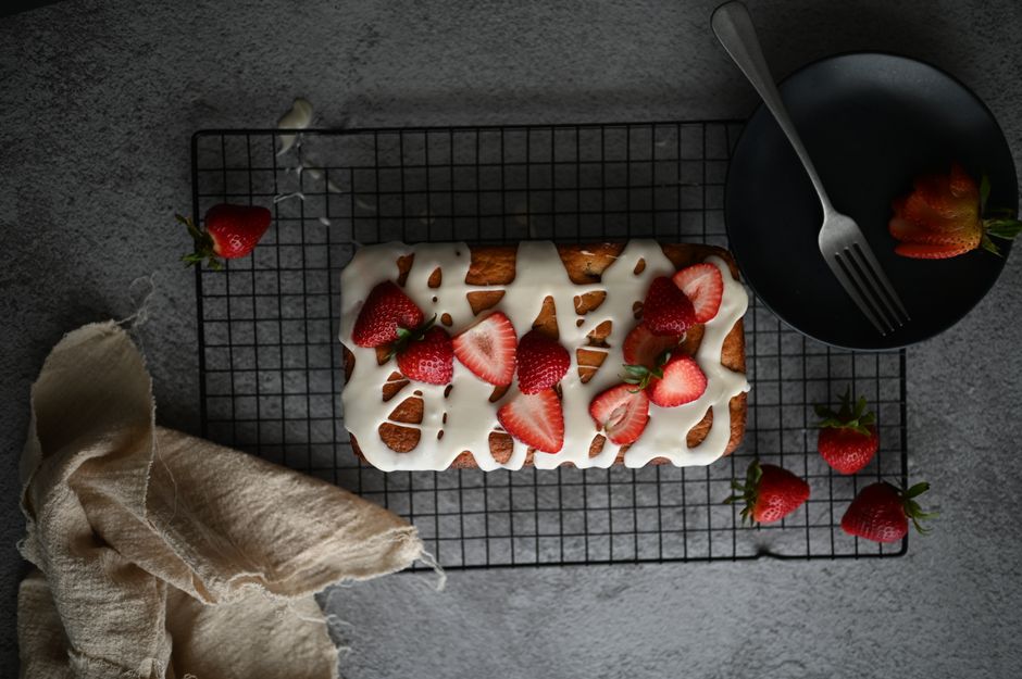 Top view of a flavorful strawberry iced cake on a cooling rack with fresh strawberries.