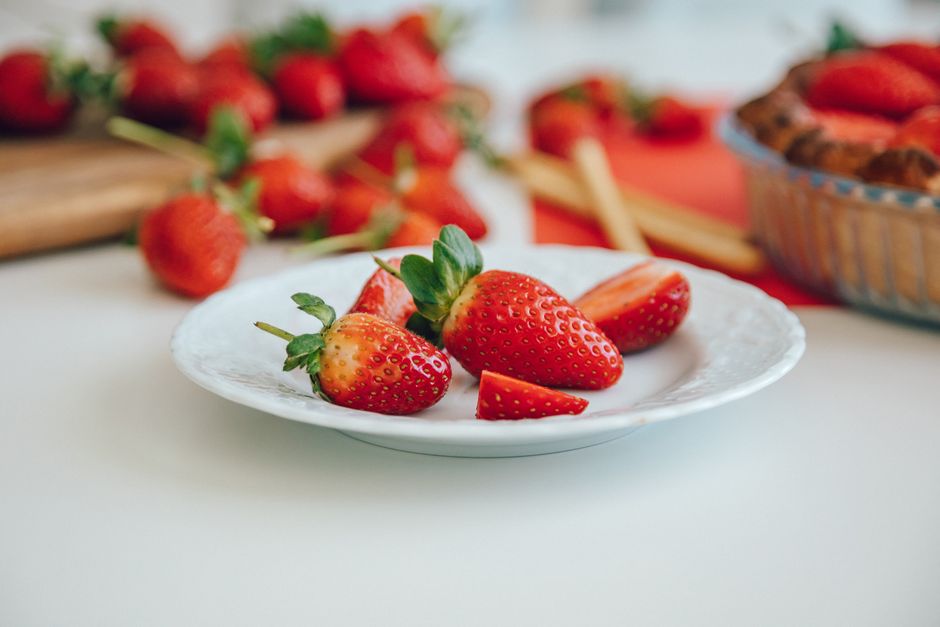 Close-up of ripe strawberries on a ceramic plate with a blurred background.