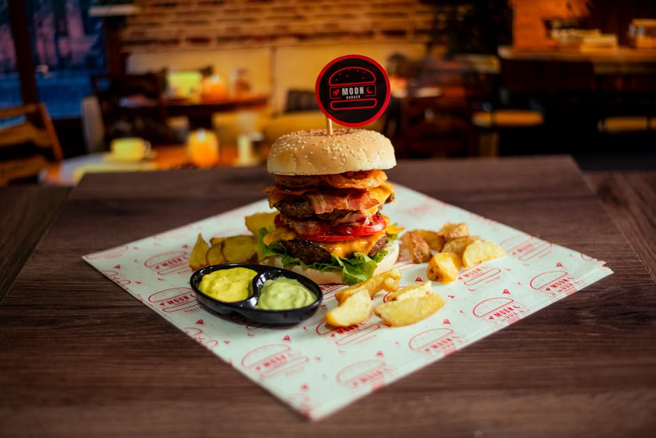 Delicious gourmet burger with crispy bacon, fresh veggies, and potato wedges served in a cozy setting.