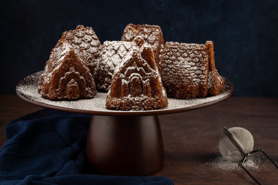 Delicious chocolate cakes on a dark wooden cake stand, dusted with powdered sugar.